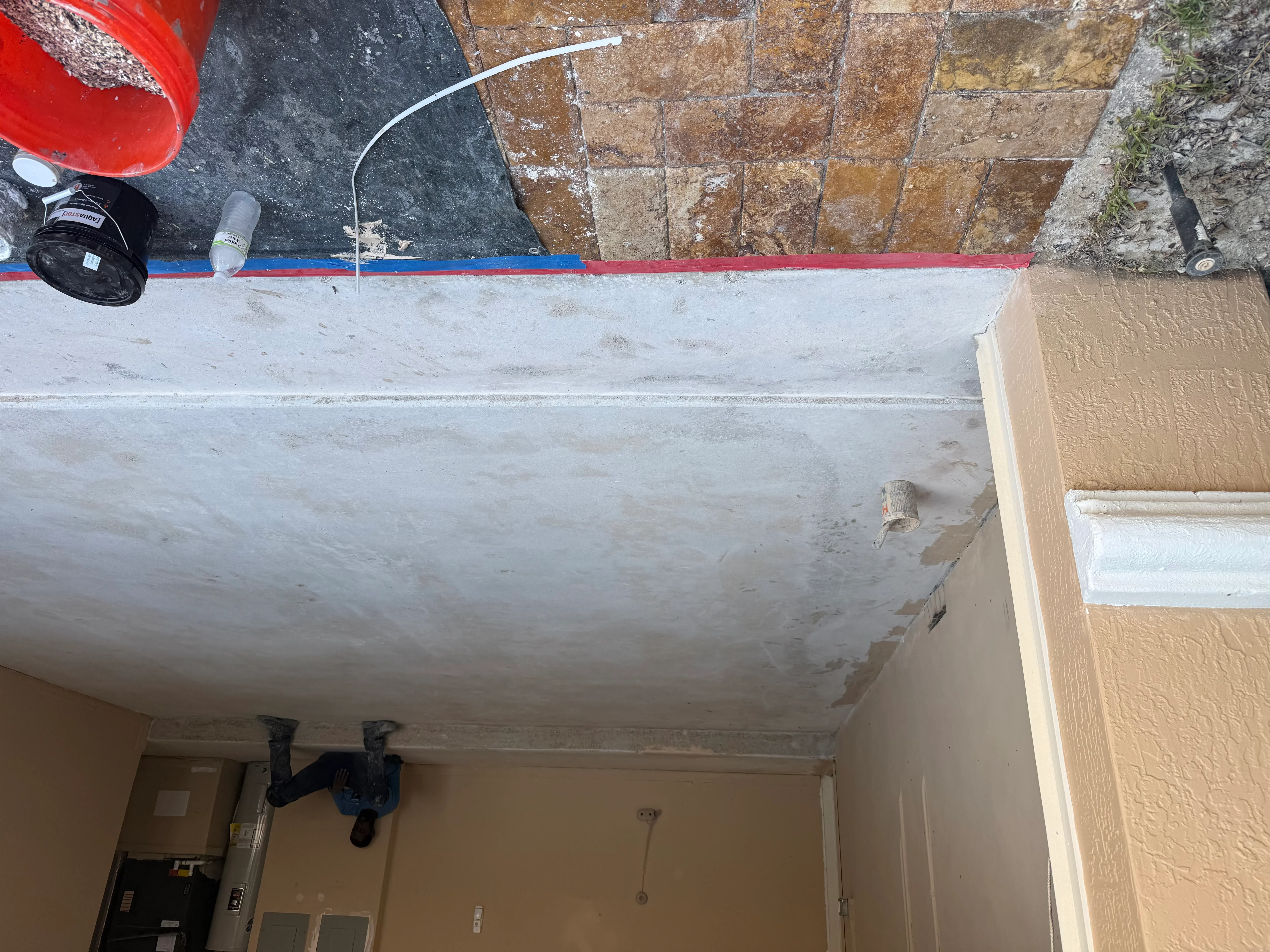 Concrete ceiling with patched repairs, blue and red tape lines, and preparation materials