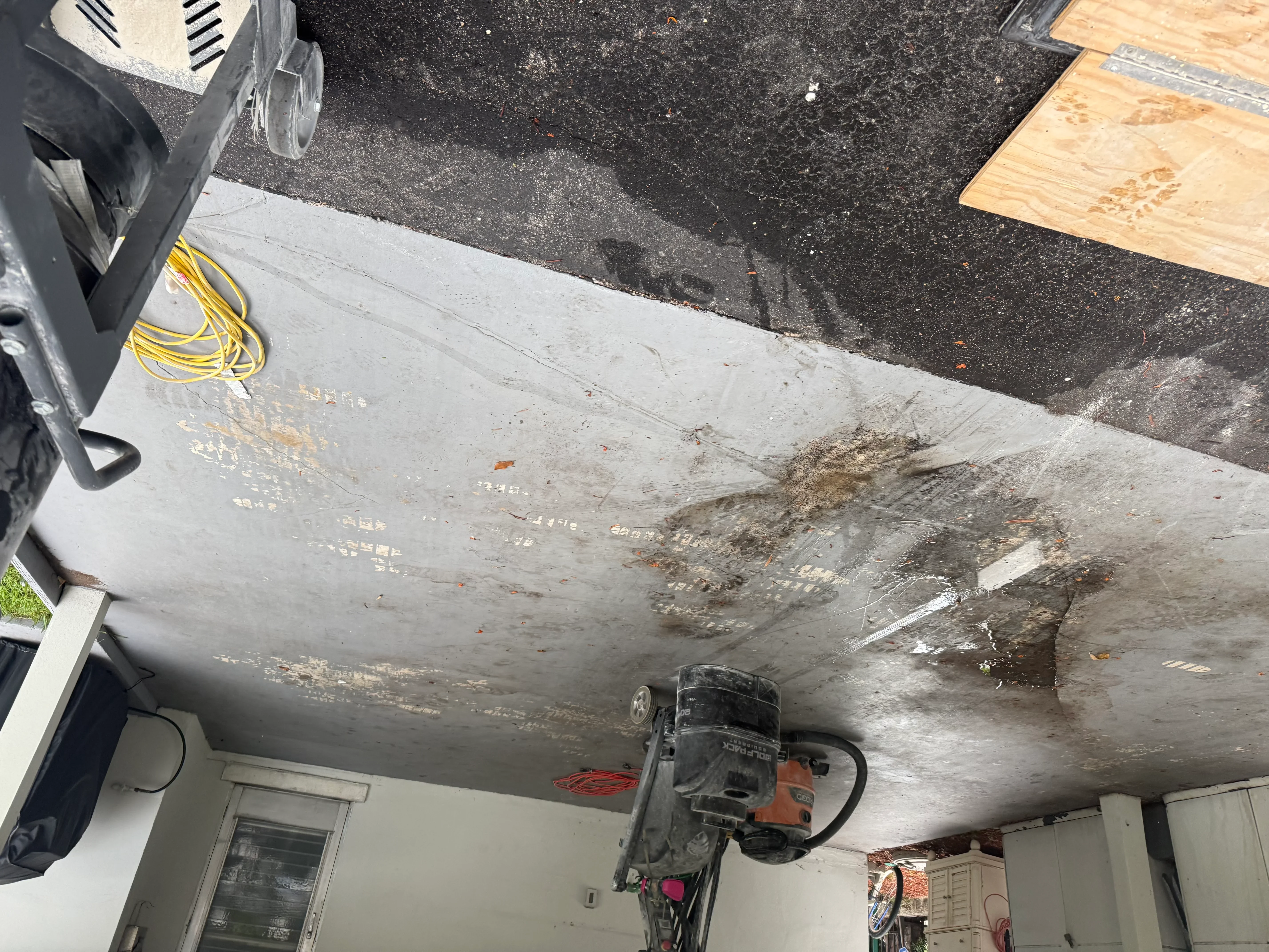Concrete ceiling with deterioration, staining, and repair work in progress using power tools
