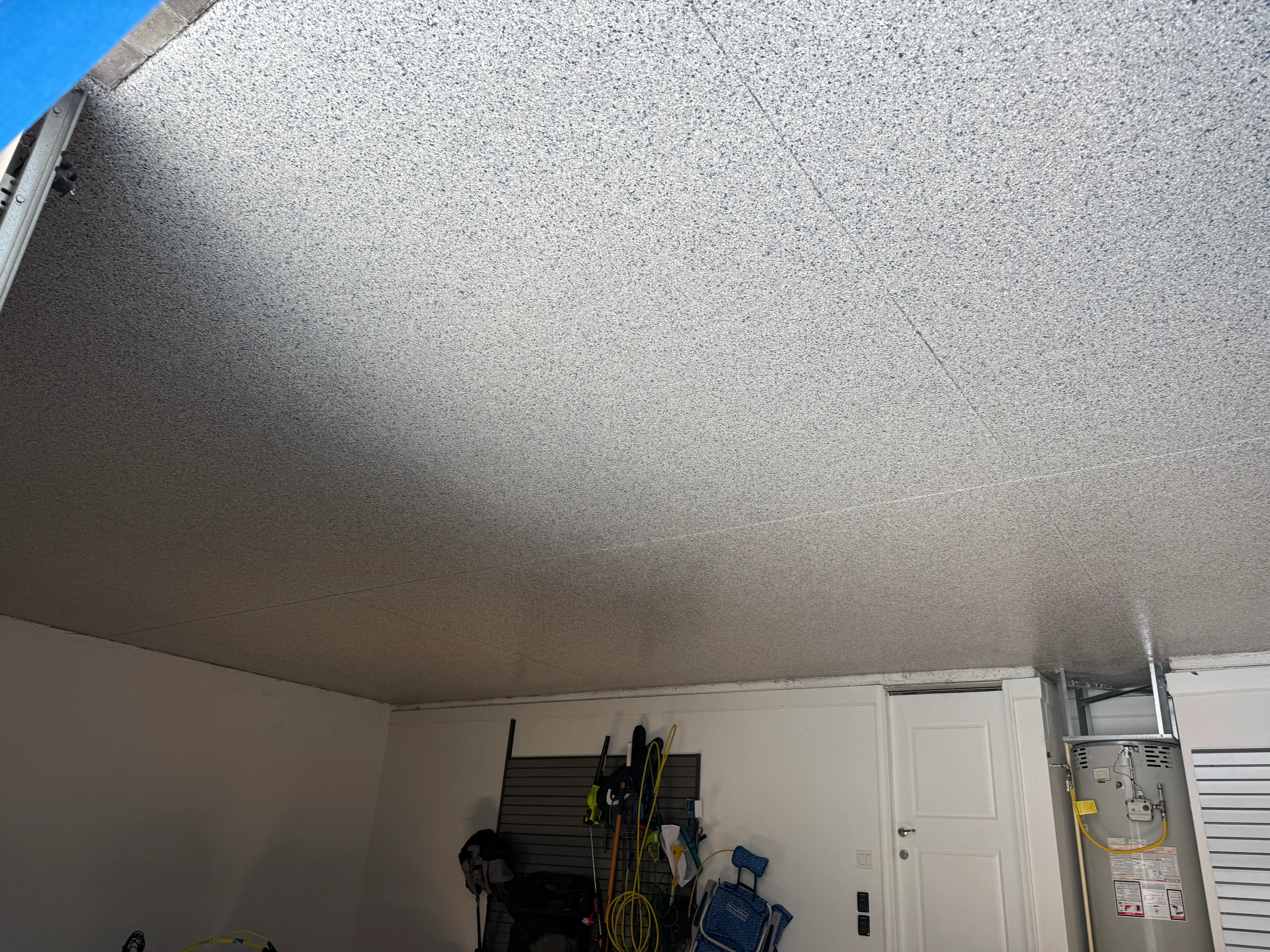 Gray textured concrete coating applied to garage ceiling with white walls below